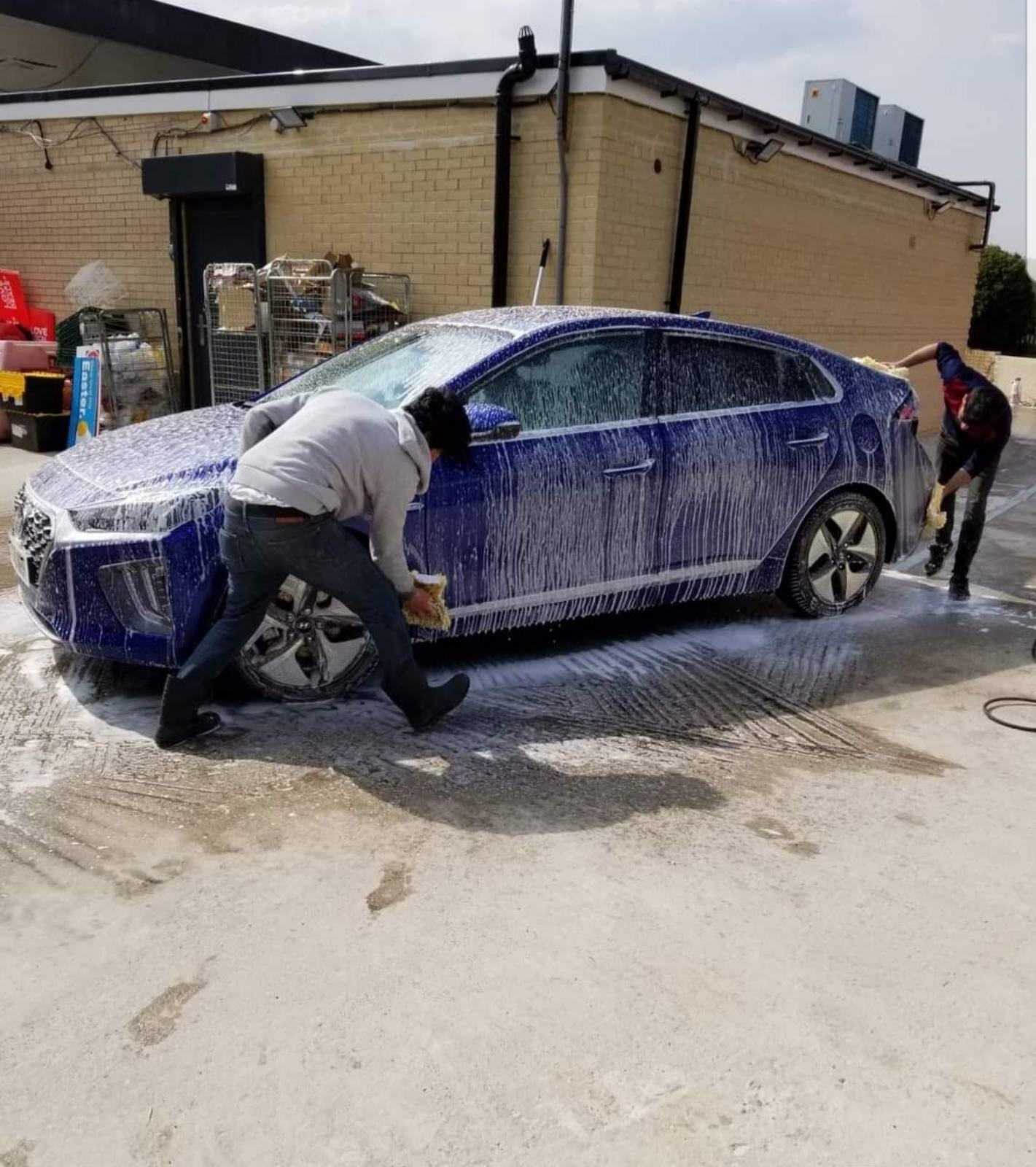 The team hand washing a blue car at Stepping Stones